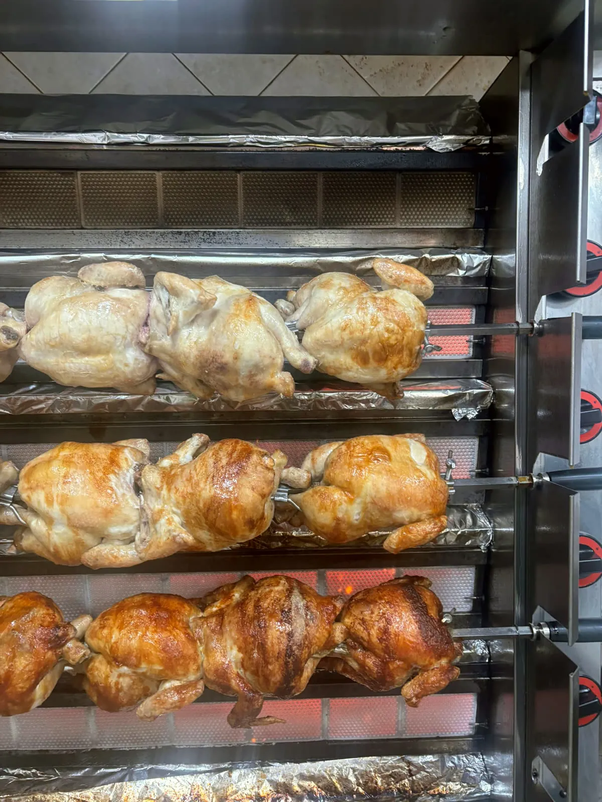 Pollos asados girando en el horno de la tienda
